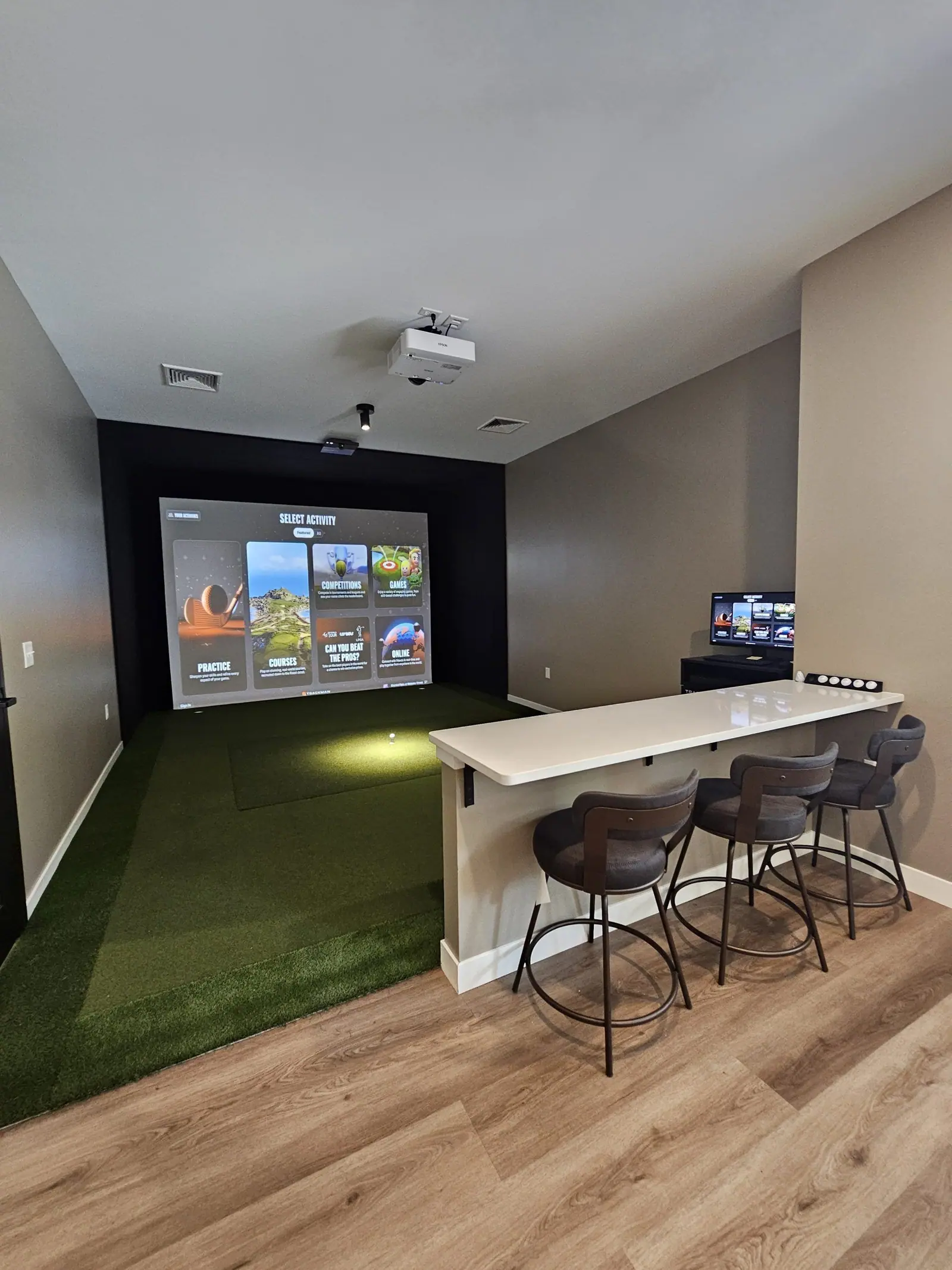 TrackMan golf simulator room with turf hitting area and bar seating