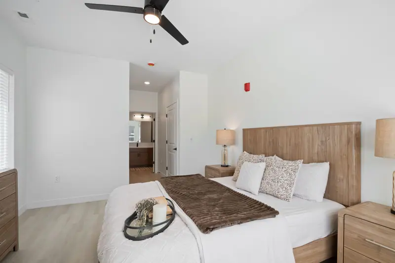 Bedroom with ceiling fan and a view into the bathroom